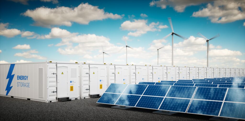 Battery storage units are stationed among solar panels and wind turbines.